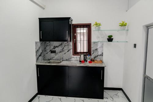 a kitchen with black cabinets and a counter top at Transit Heaven - 10 Minutes to Airport in Katunayake