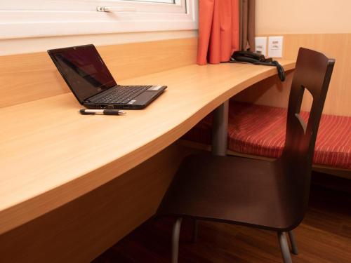 a laptop computer sitting on top of a wooden desk at ibis Contagem Ceasa in Contagem