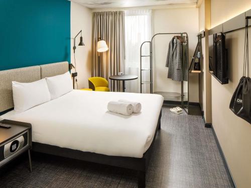 a hotel room with a large white bed and a chair at ibis London Blackfriars in London