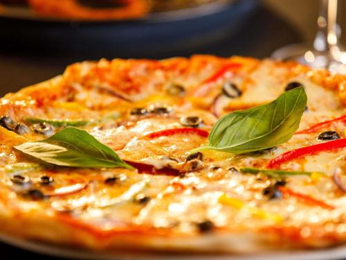 a pizza with green leaves on top of it at ibis London Blackfriars in London