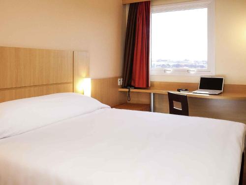a hotel room with a bed and a desk with a laptop at ibis Ourinhos in Ourinhos