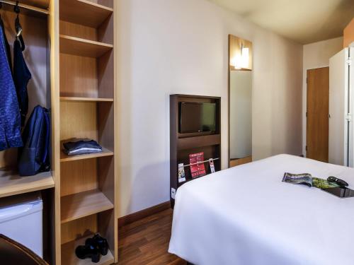a room with a bed and a tv and shelves at ibis Ourinhos in Ourinhos