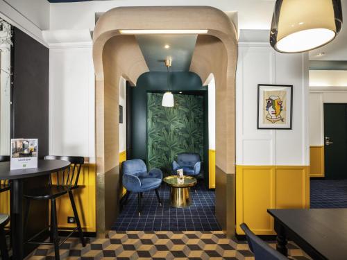 a restaurant with blue chairs and a yellow wall at ibis Styles Paris Cadet Lafayette in Paris