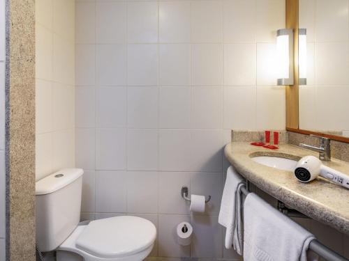 a bathroom with a toilet and a sink at ibis Ourinhos in Ourinhos
