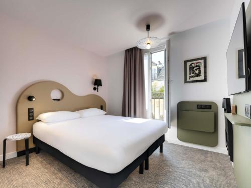 a bedroom with a large white bed and a window at ibis Styles Paris Cadet Lafayette in Paris