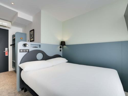 a bedroom with a white bed with a blue headboard at ibis Styles Paris Cadet Lafayette in Paris
