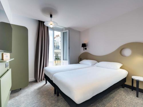 a hotel room with two beds and a window at ibis Styles Paris Cadet Lafayette in Paris
