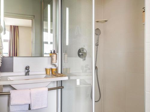 a bathroom with a sink and a shower at Mercure Lille Roubaix Grand Hôtel in Roubaix