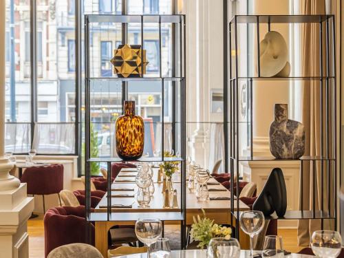 a dining room with a table with vases on display at Mercure Lille Roubaix Grand Hôtel in Roubaix
