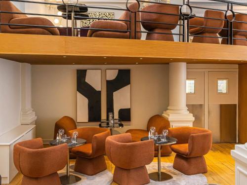 a restaurant with tables and chairs under a loft at Mercure Lille Roubaix Grand Hôtel in Roubaix