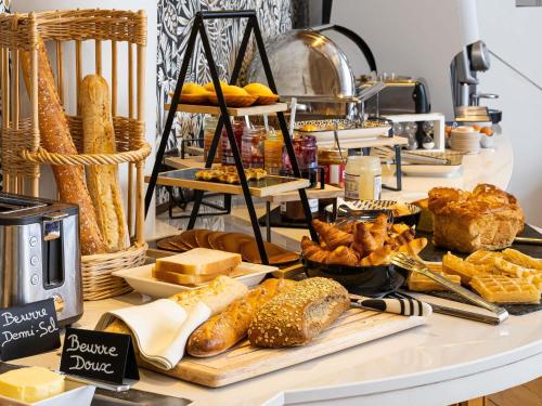 a buffet of bread and pastries on a table at Mercure Lille Roubaix Grand Hôtel in Roubaix