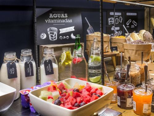 a bowl of fruit on a table with bottles of milk at ibis Berlin Kurfuerstendamm - neu renoviert in Berlin