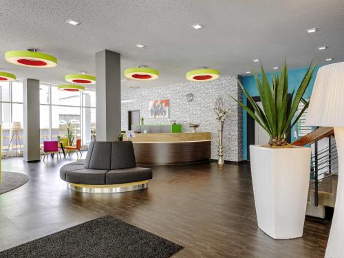 an office lobby with a black chair and a desk at ibis Styles Arnsberg - Neheim in Arnsberg