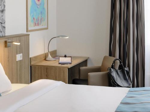 a hotel room with a bed and a chair and a table at ibis Styles Arnsberg - Neheim in Arnsberg