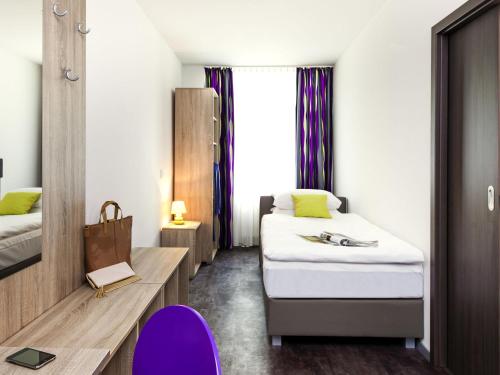 a room with two beds and a table and a chair at ibis Styles Arnsberg - Neheim in Arnsberg
