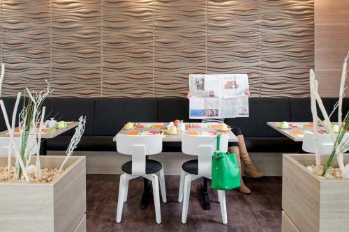 a dining room with two tables and white chairs at ibis Styles Arnsberg - Neheim in Arnsberg