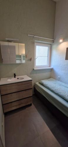 a bathroom with a sink and a bed and a mirror at Casa Cool - Climatisation réversible et Nature in Virton