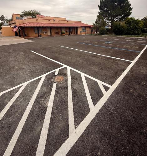a parking lot with white lines in front of a building at Adobe Rose Boutique Inn in Artesia