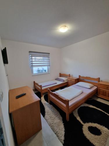 a room with two beds and a table and a desk at Sobe Kod Ćobe in Matuzići