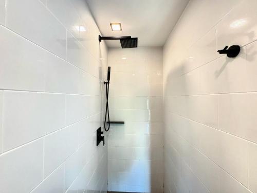 a shower in a bathroom with white tiles at Utopia Loft Condo Naiharn Beach in Nai Harn Beach