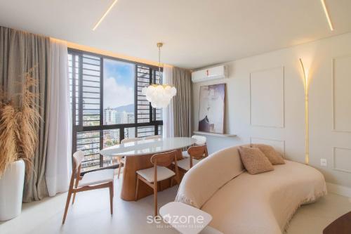 a bedroom with a bed and a table and a window at Apartamentos Bem Equipados a 100 m da Praia - EVR in Perequê