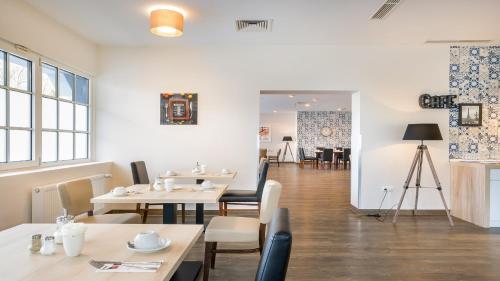 a dining room with tables and chairs and a camera at Garner Hotel Cologne Porz - Airport by IHG in Cologne