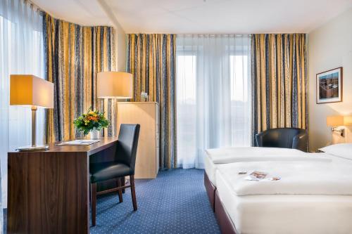 a hotel room with a bed and a desk and a bed and a bed at Garner Hotel Cologne Porz - Airport by IHG in Cologne