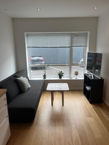 a living room with a black couch and a window at New apartment in Hoyvík in Hoyvík