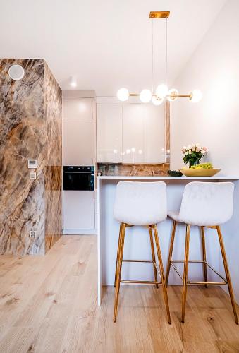 a kitchen with white cabinets and white stools at Vidok 201 in Olsztyn