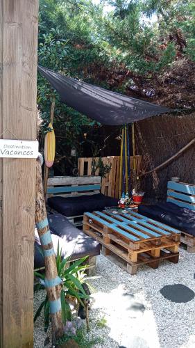 a patio with a table and an umbrella and benches at La Cabane Bordeaux St Augustin in Mérignac