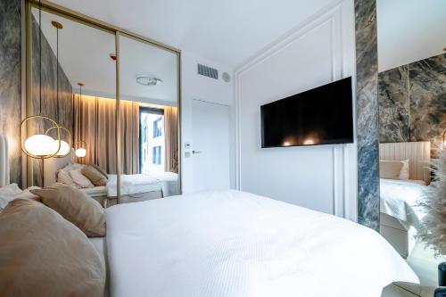 a bedroom with a white bed and a tv on a wall at Vidok 201 in Olsztyn