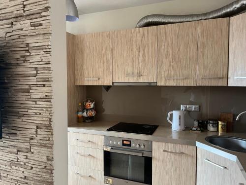 a kitchen with wooden cabinets and a stove top oven at Apartament NA WRZOSACH in Kielce