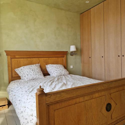 a bedroom with a large bed with a wooden headboard at Bos-en-Veld in Wingene