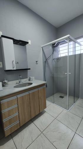 a bathroom with a shower and a sink and a mirror at Casa no Centro de São Roque - SP in São Roque