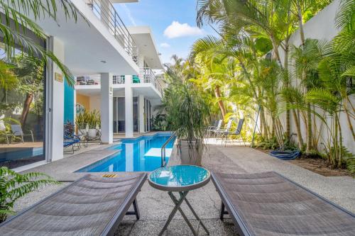 an outdoor swimming pool with a bench and palm trees at Maravilla Suites - Bucerias Golden Zone in Bucerías