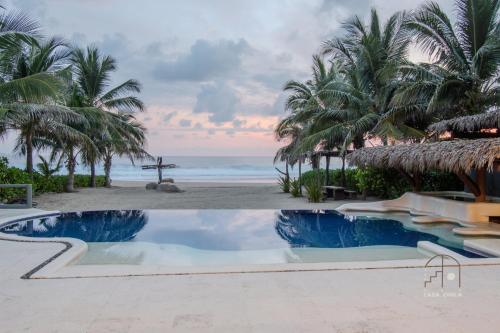 a resort swimming pool with a view of the beach at Spectacular House with a Private Beach Front in Ixtapa-Zihuatanejo International