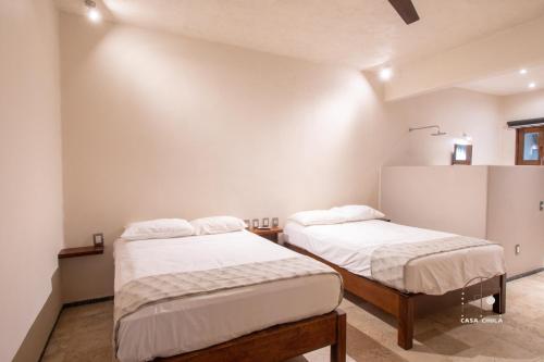 two beds in a room with white walls at Spectacular House with a Private Beach Front in Ixtapa-Zihuatanejo International