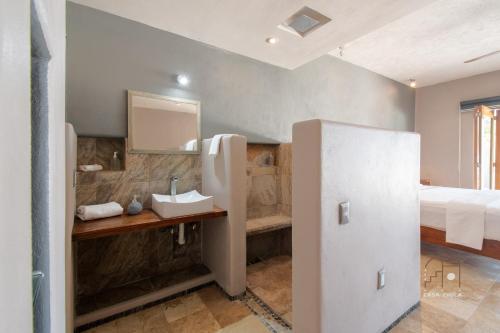 a bathroom with a sink and a bed and a mirror at Spectacular House with a Private Beach Front in Ixtapa-Zihuatanejo International