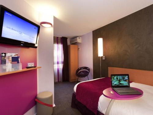 a hotel room with a bed and a laptop on a table at ibis Styles Bourg-en-Bresse Centre in Bourg-en-Bresse
