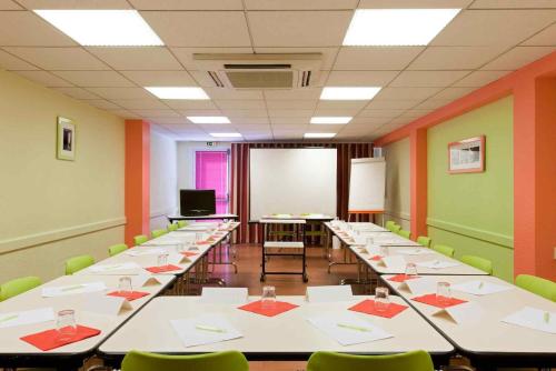 a classroom with long tables and chairs and a screen at ibis Styles Bourg-en-Bresse Centre in Bourg-en-Bresse