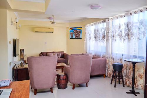 a living room with a couch and chairs and a table at 3 - bedroom duplex apartment in upanga in Dar es Salaam