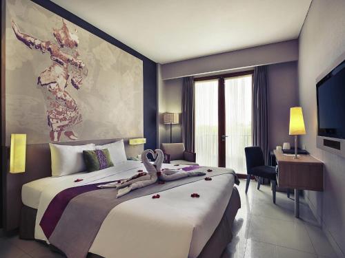 a hotel room with a large bed with flowers on it at Mercure Bali Nusa Dua in Nusa Dua
