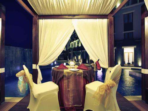 a dining room with a table and white chairs at Mercure Bali Nusa Dua in Nusa Dua