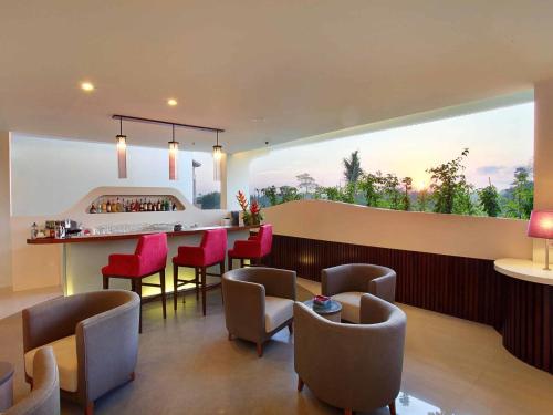 a room with a bar and chairs and a large window at Mercure Bali Nusa Dua in Nusa Dua