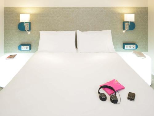 a white bed with a pair of shoes and a pink purse at ibis Styles Tours Centre in Tours