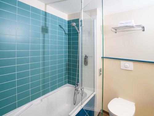 a bathroom with a toilet and a shower with blue tiles at ibis Styles Tours Centre in Tours