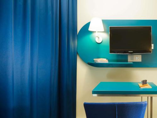 a room with a blue curtain and a desk with a television at ibis Styles Tours Centre in Tours