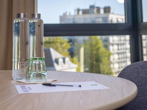 a bottle and a pen on a table with a window at ibis Styles Tours Centre in Tours