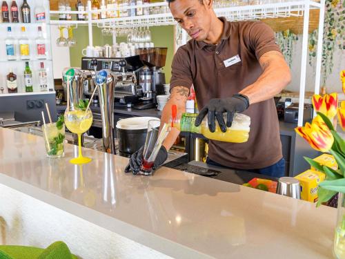a man is preparing a drink in a kitchen at ibis Styles Tours Centre in Tours