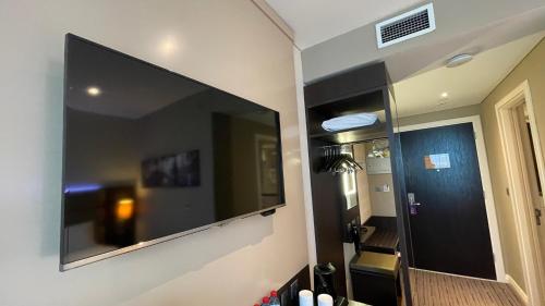 a large flat screen tv on the wall of a bathroom at Premier Inn Doha Education City in Doha
